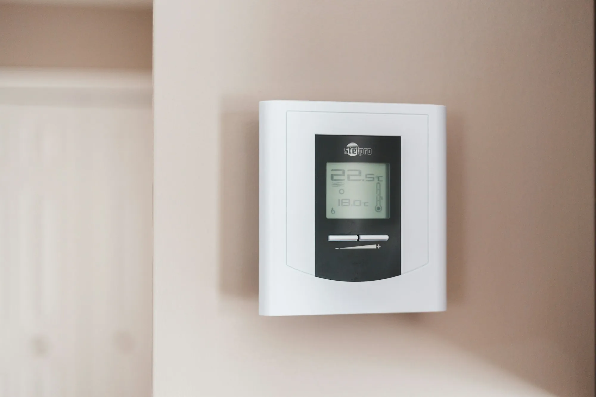 Programmable digital thermostat on a white wall